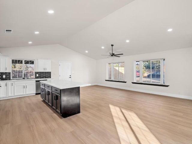 kitchen with tasteful backsplash, lofted ceiling, a center island, white cabinetry, and light wood-type flooring