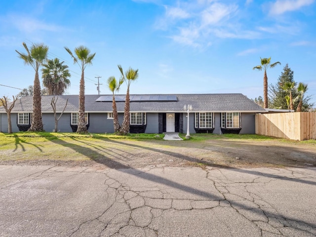 single story home with a front lawn and solar panels