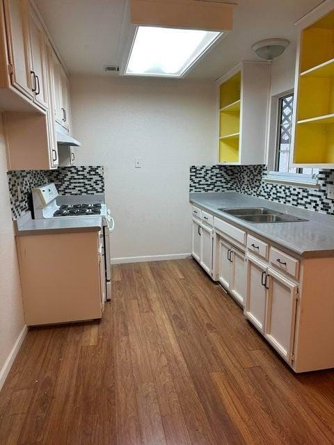 kitchen with backsplash, light hardwood / wood-style flooring, white range with electric stovetop, and sink