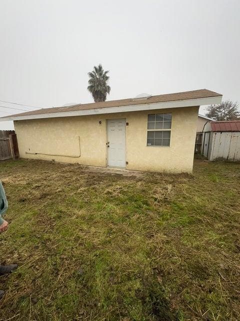 back of house featuring a lawn and a shed