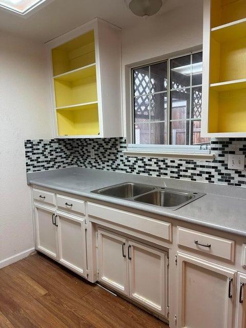 kitchen with decorative backsplash, hardwood / wood-style floors, and white cabinets