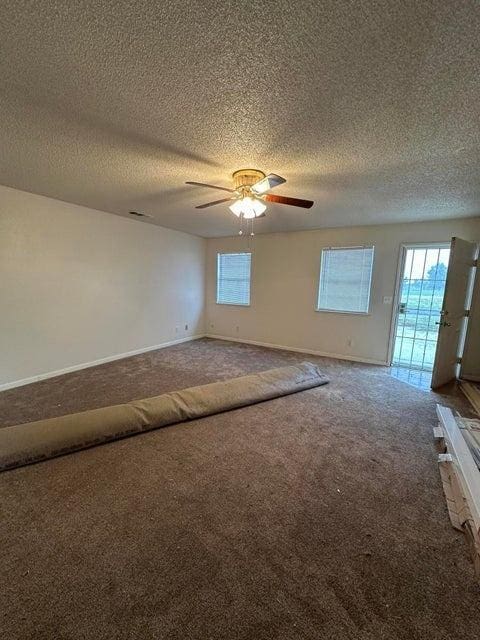 spare room with carpet, a textured ceiling, and ceiling fan