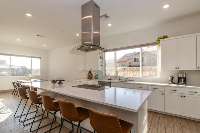 kitchen with island range hood, sink, light hardwood / wood-style flooring, white cabinets, and a center island