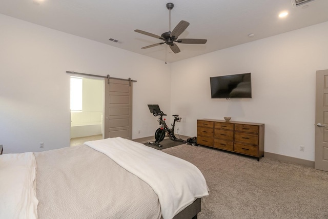 bedroom with light carpet, a barn door, ensuite bath, and ceiling fan