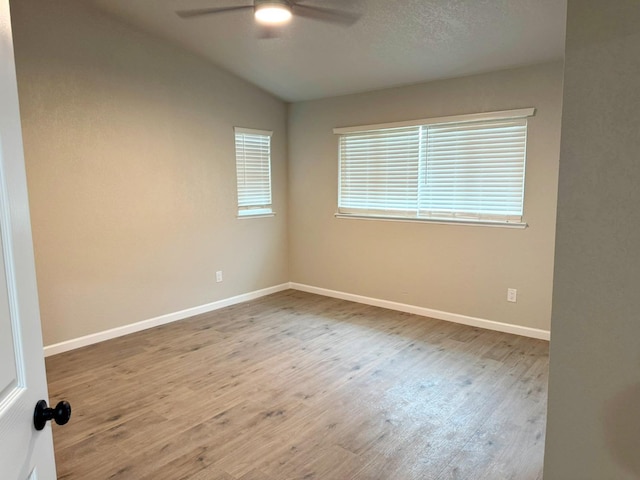 spare room featuring baseboards, a ceiling fan, vaulted ceiling, and wood finished floors