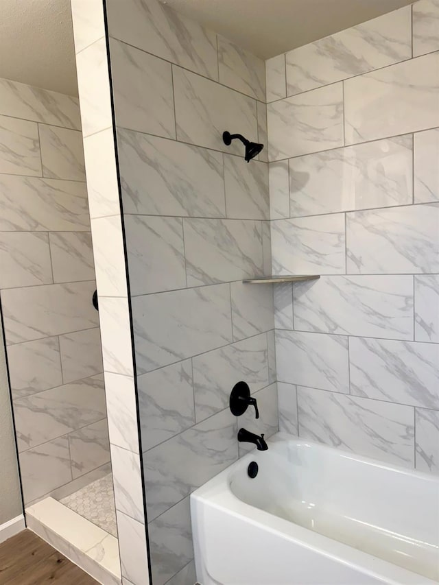 bathroom featuring wood finished floors and washtub / shower combination