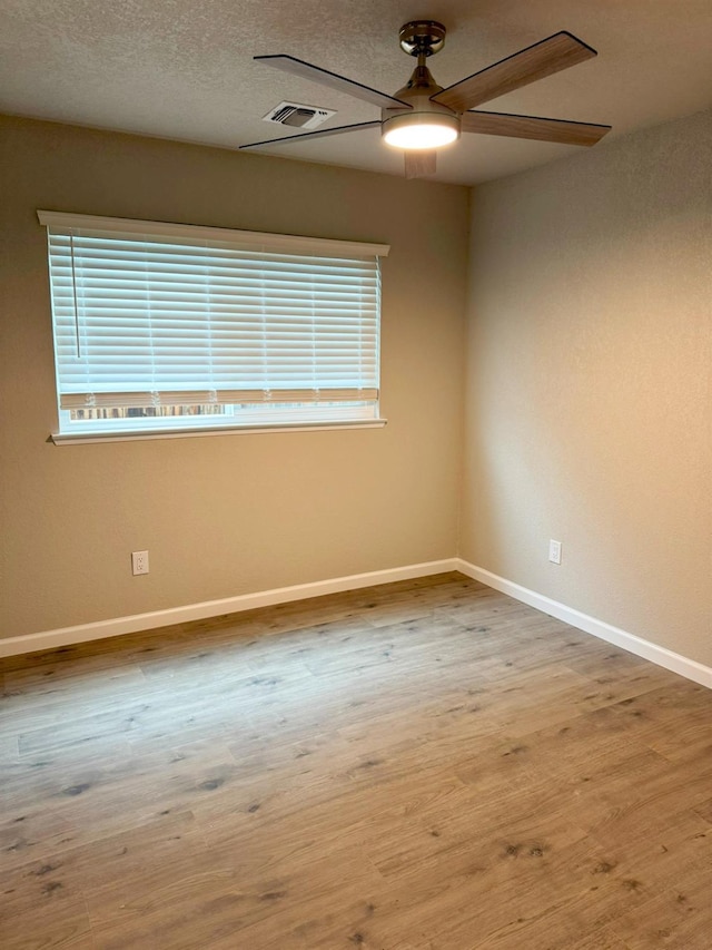 empty room featuring ceiling fan, a wealth of natural light, light wood-style flooring, and baseboards