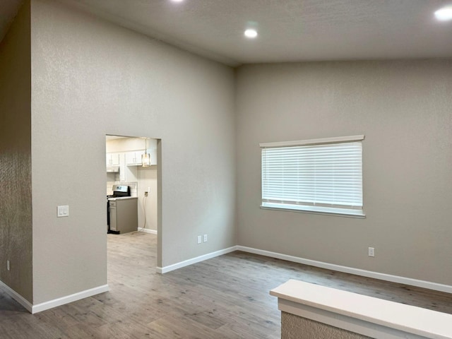 empty room with light wood-style floors, recessed lighting, and baseboards