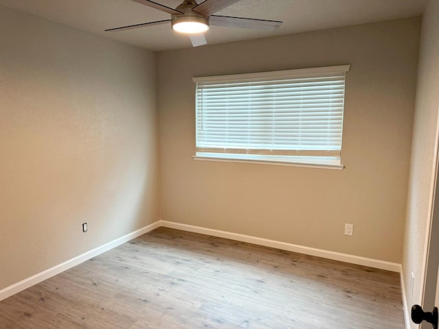 spare room featuring a ceiling fan, baseboards, and wood finished floors