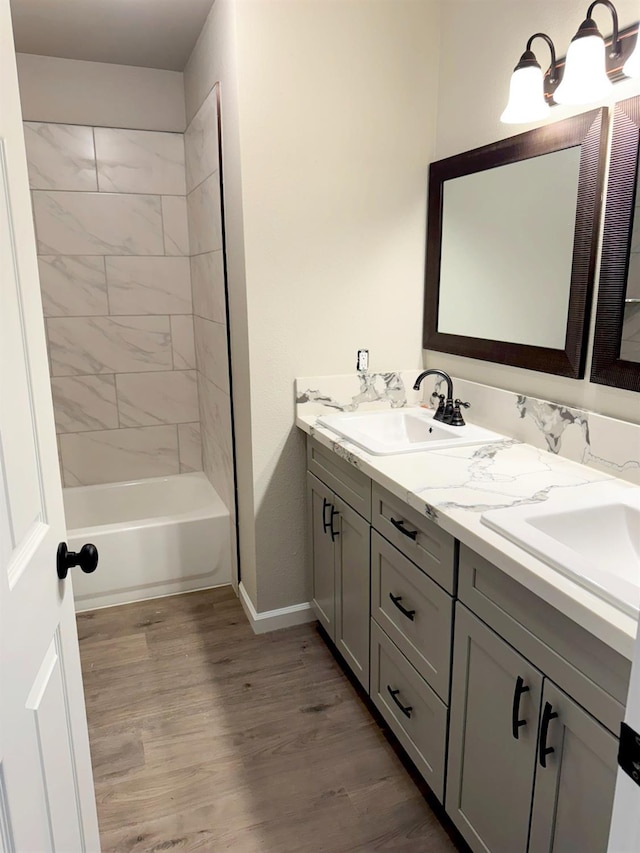 full bathroom featuring double vanity, wood finished floors, tub / shower combination, and a sink