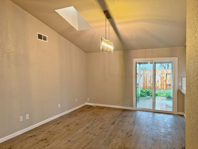 unfurnished room featuring vaulted ceiling with skylight, baseboards, visible vents, wood finished floors, and a chandelier