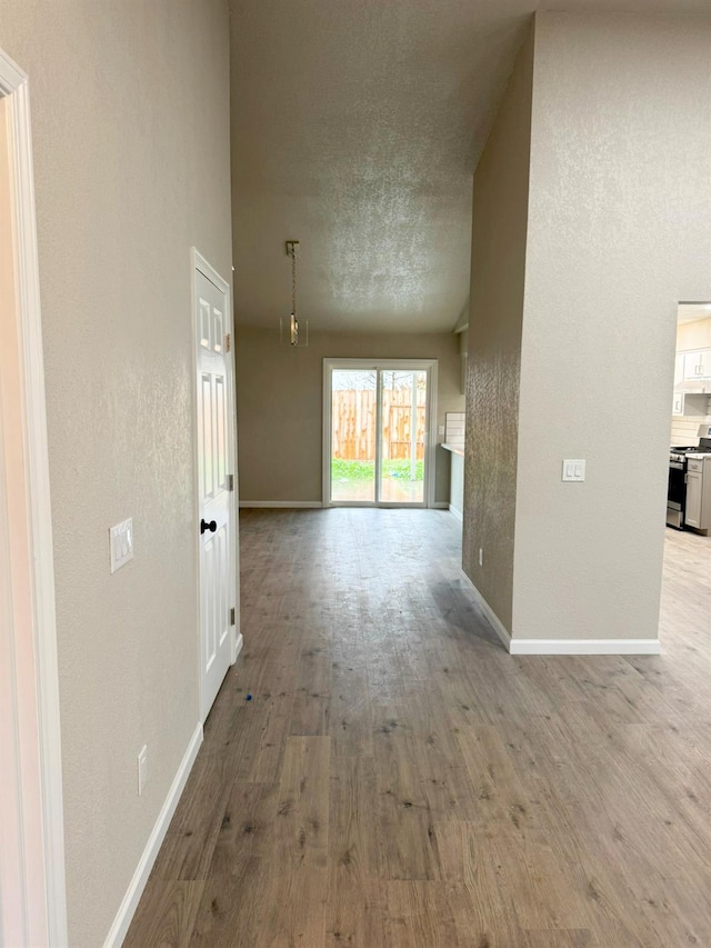 unfurnished living room featuring light wood finished floors, baseboards, and a textured ceiling