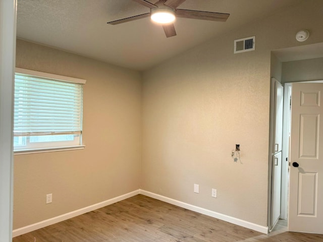 spare room with a ceiling fan, light wood-type flooring, visible vents, and baseboards