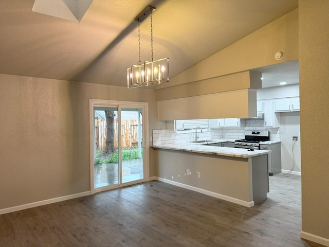 kitchen featuring stainless steel stove, hanging light fixtures, white cabinetry, a sink, and a peninsula