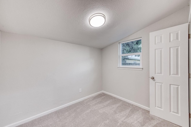 unfurnished room with a textured ceiling, light carpet, and lofted ceiling