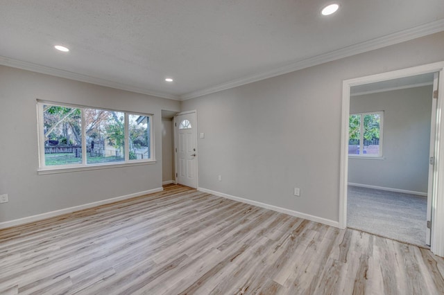 empty room with plenty of natural light, light hardwood / wood-style floors, and ornamental molding