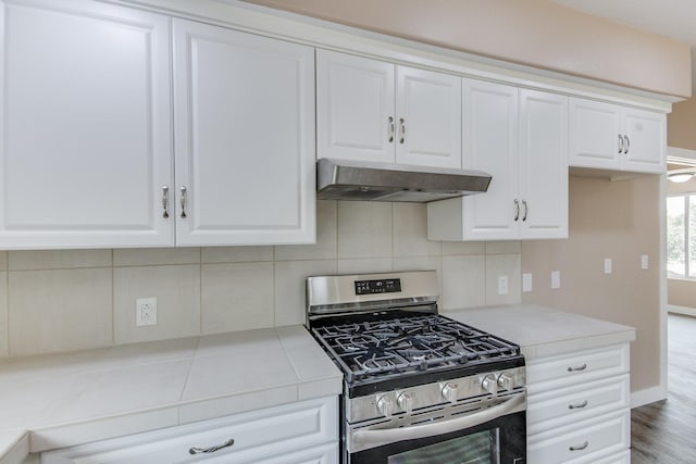 kitchen with hardwood / wood-style floors, backsplash, white cabinetry, and stainless steel gas range