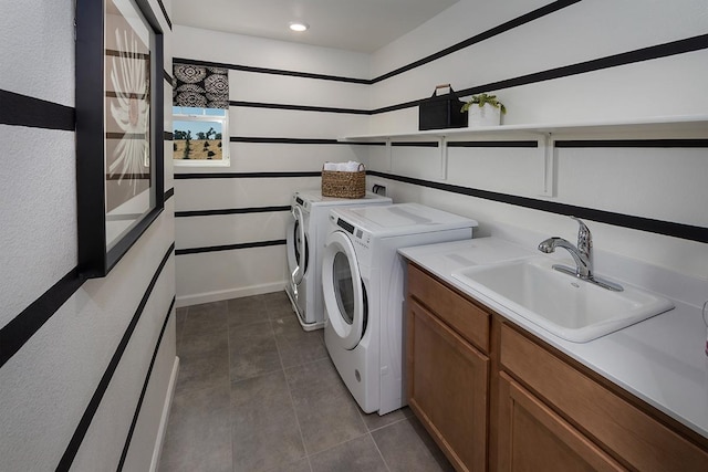 laundry room featuring washing machine and dryer, sink, cabinets, and dark tile patterned flooring