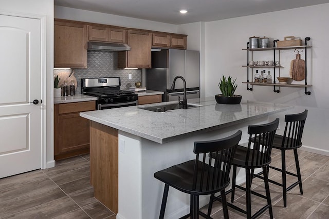 kitchen featuring a breakfast bar area, light stone countertops, sink, and stainless steel appliances