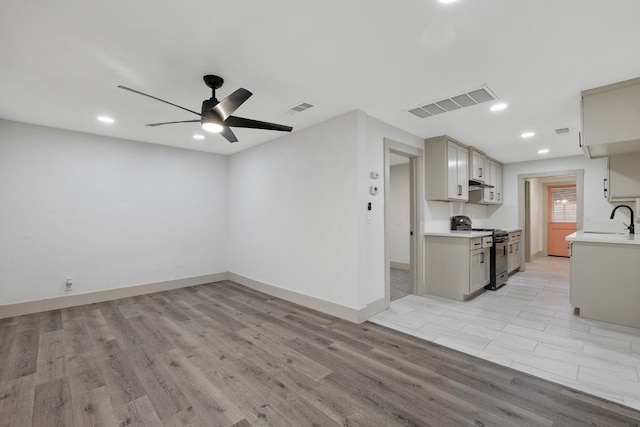 kitchen featuring light wood-type flooring, ceiling fan, sink, range, and gray cabinets