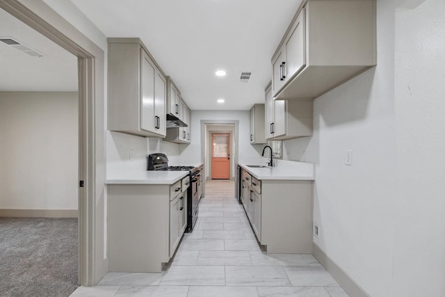 kitchen with gray cabinetry, black gas stove, light colored carpet, and sink