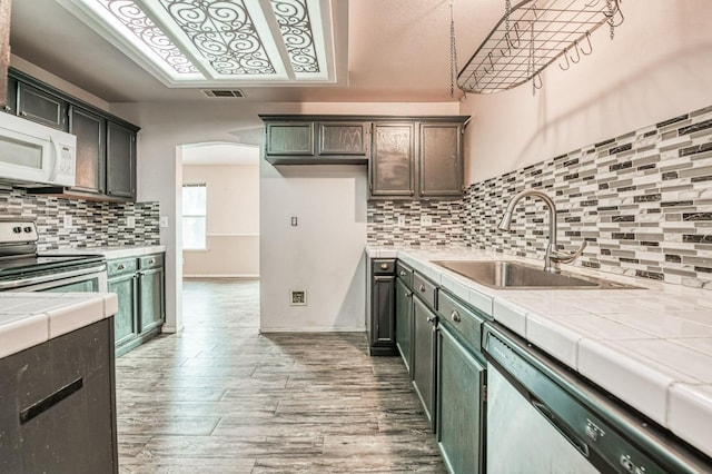 kitchen with stainless steel range with electric stovetop, dishwashing machine, hardwood / wood-style floors, and tile countertops