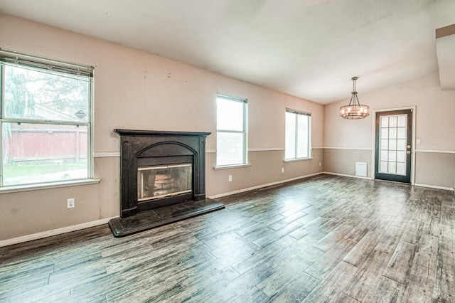 unfurnished living room featuring hardwood / wood-style floors, an inviting chandelier, and lofted ceiling