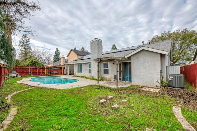 back of property with solar panels, a fenced in pool, cooling unit, a yard, and a patio