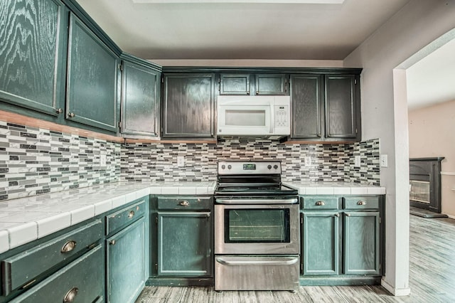 kitchen featuring decorative backsplash, light hardwood / wood-style floors, and stainless steel electric range oven