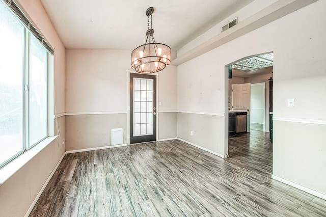 spare room with hardwood / wood-style flooring, a healthy amount of sunlight, and an inviting chandelier