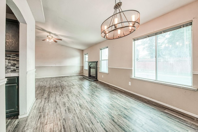 unfurnished living room with ceiling fan with notable chandelier and hardwood / wood-style flooring