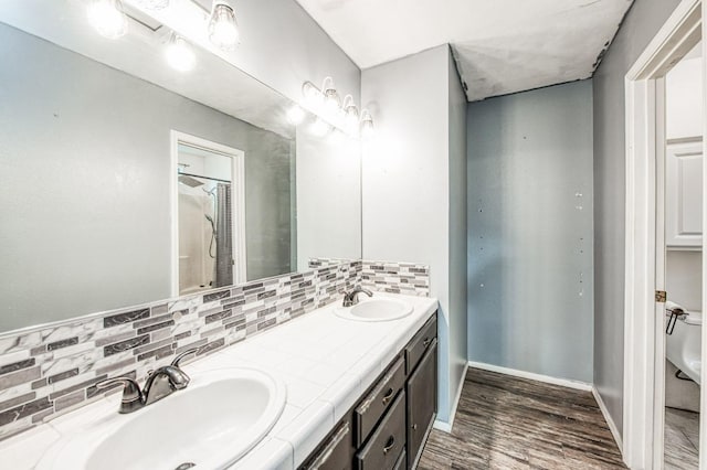 bathroom with backsplash, walk in shower, vanity, and hardwood / wood-style flooring