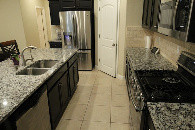 kitchen with sink, light tile patterned floors, stainless steel appliances, tasteful backsplash, and light stone countertops