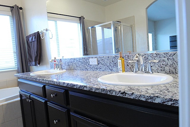 bathroom with independent shower and bath, vanity, and a wealth of natural light