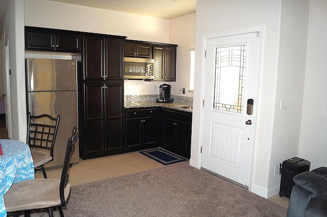 kitchen featuring appliances with stainless steel finishes, light colored carpet, and light stone counters