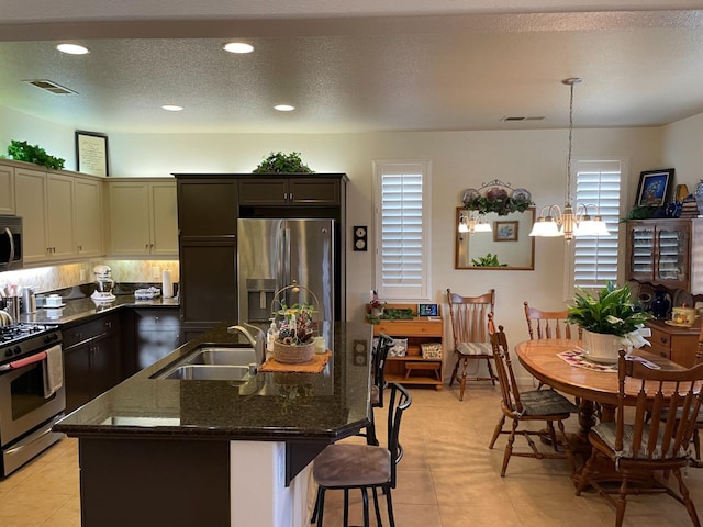 kitchen featuring pendant lighting, sink, an island with sink, stainless steel appliances, and a chandelier