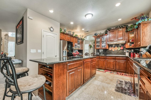 kitchen featuring appliances with stainless steel finishes, a breakfast bar, a textured ceiling, sink, and a kitchen island