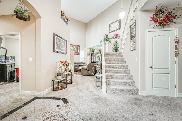 entrance foyer featuring a towering ceiling and carpet floors