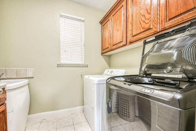 laundry room with cabinets, light tile patterned floors, and separate washer and dryer