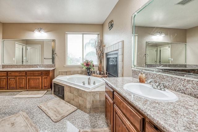 bathroom featuring vanity and tiled bath