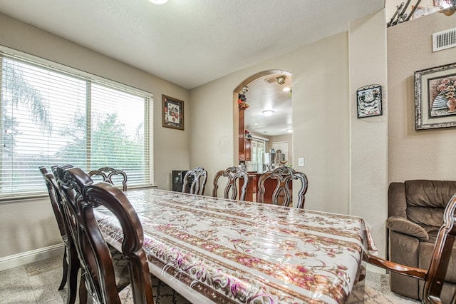 carpeted dining area with a textured ceiling