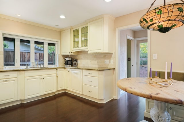 kitchen featuring light stone counters, ornamental molding, dark wood-type flooring, and tasteful backsplash