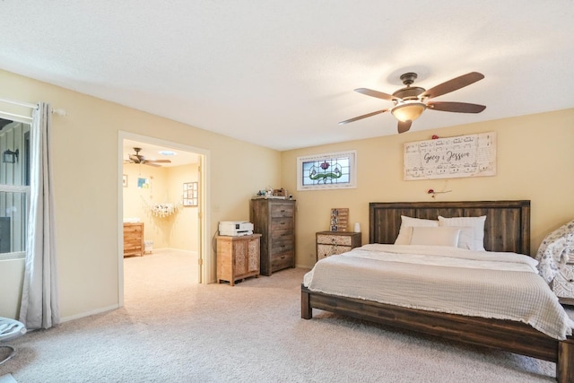 carpeted bedroom with ensuite bathroom and ceiling fan