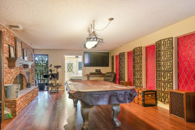 playroom with a textured ceiling, ceiling fan, hardwood / wood-style flooring, billiards, and a fireplace