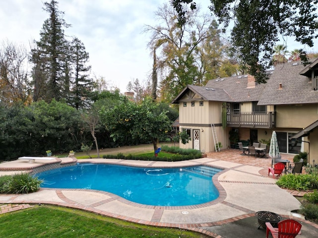 view of pool with a diving board and a patio