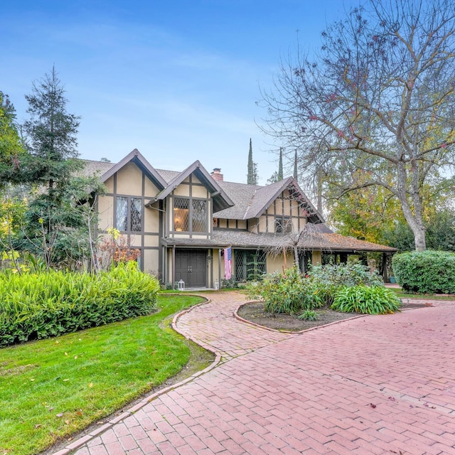 tudor-style house featuring a front yard and a garage