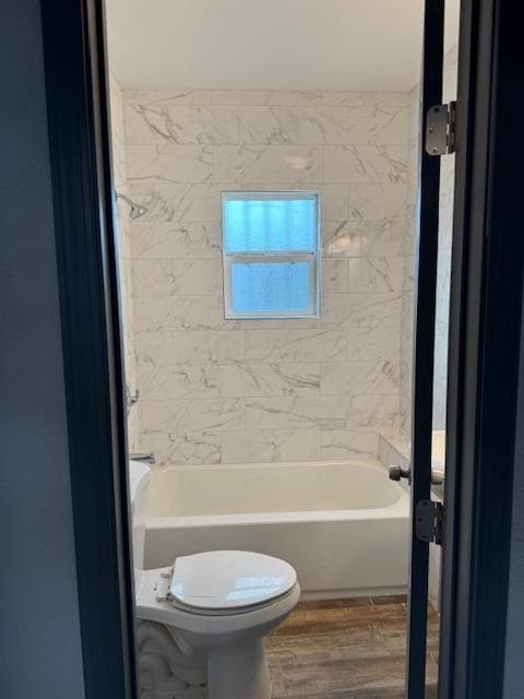 bathroom featuring hardwood / wood-style floors, tiled shower / bath combo, and toilet