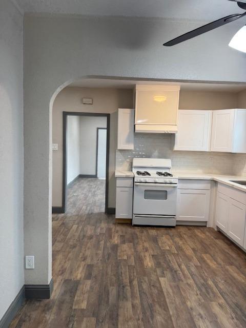 kitchen with backsplash, white cabinetry, dark wood-type flooring, and white range with gas cooktop