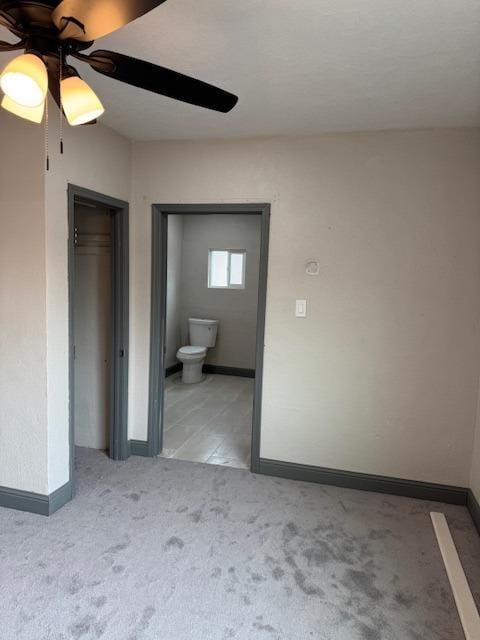 unfurnished bedroom with light carpet, connected bathroom, a closet, and ceiling fan