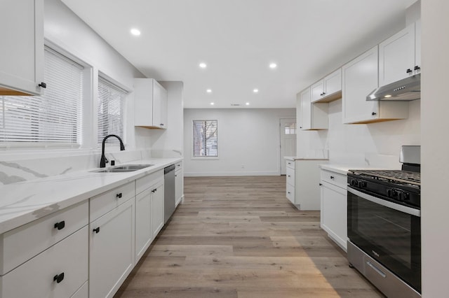 kitchen with white cabinets, sink, light wood-type flooring, light stone counters, and stainless steel appliances